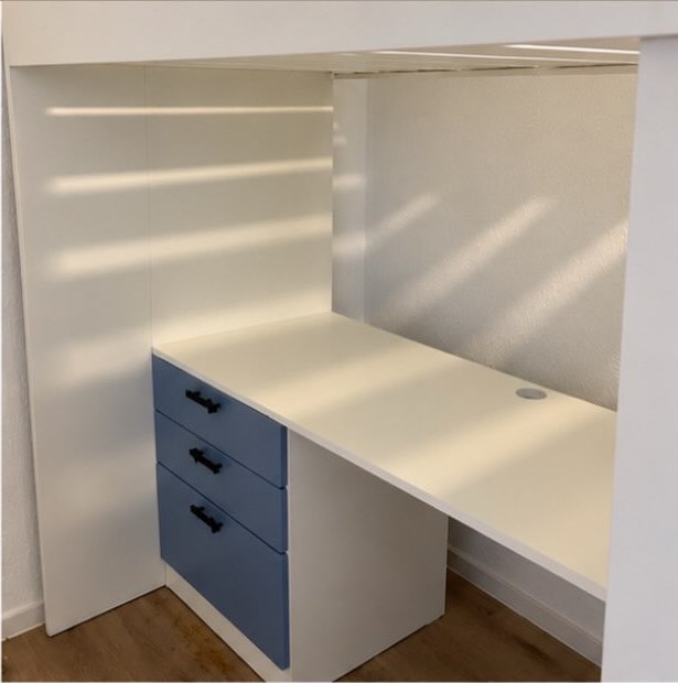 Schreibtisch mit drei blauen Schubladen unter dem Hochbett